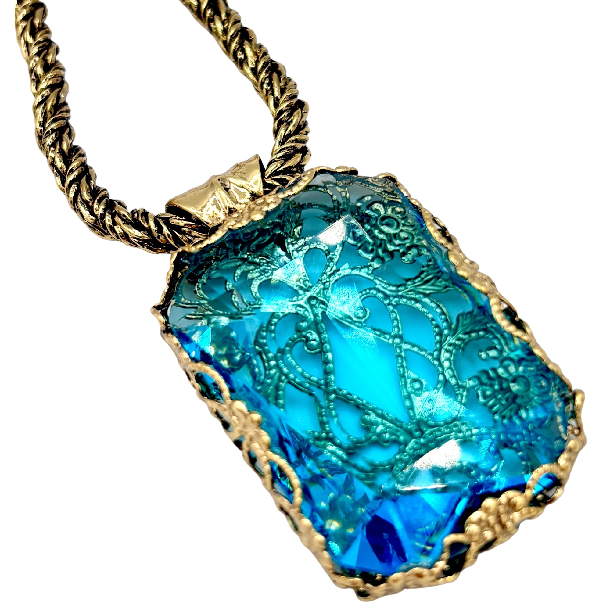 Collier avec pendentif en cristal bleu facetté, motifs gravés et monture dorée sur chaîne torsadée