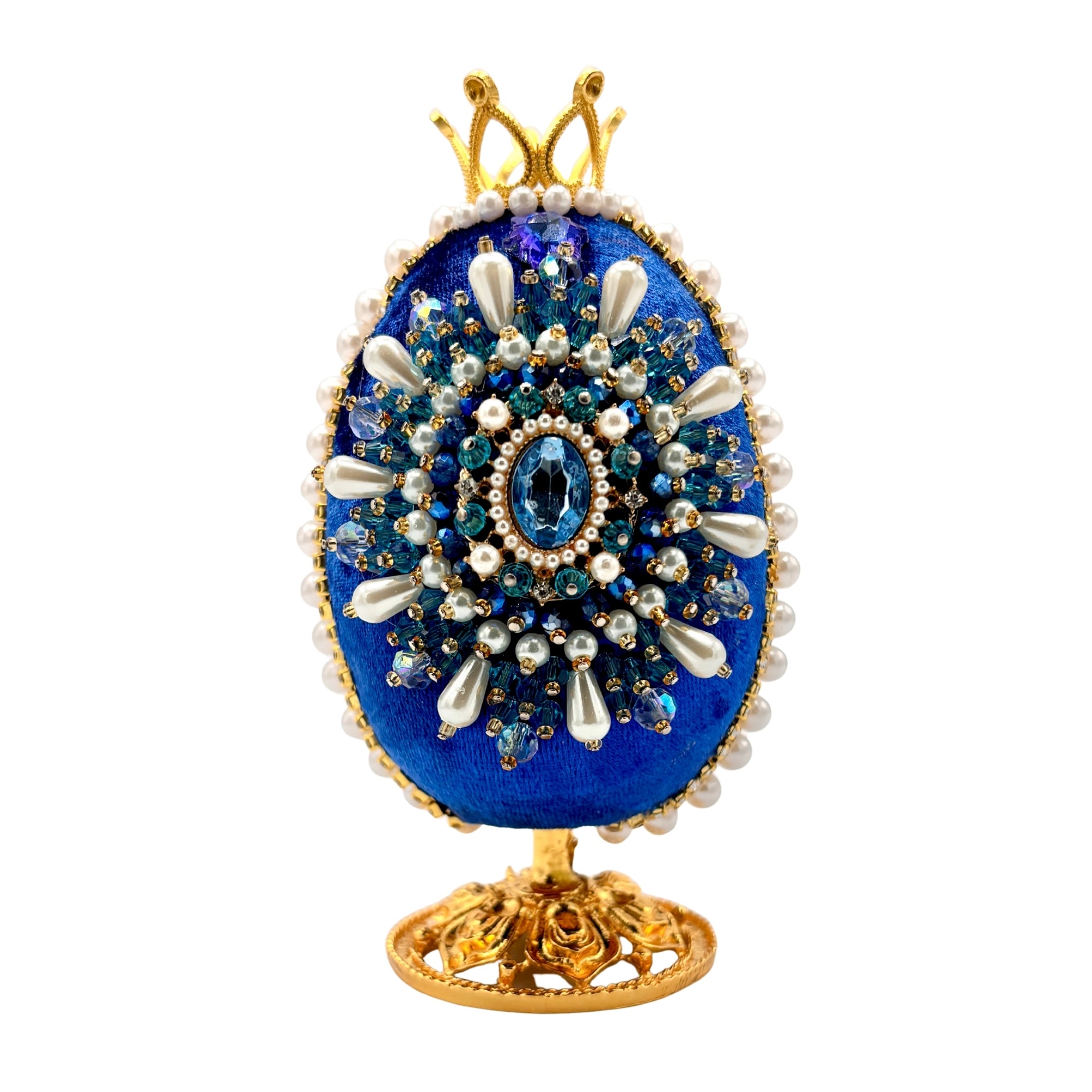 Œuf décoratif bleu sur pied doré, orné de perles blanches, cristaux et cabochon central bleu, style précieux et artisanal
