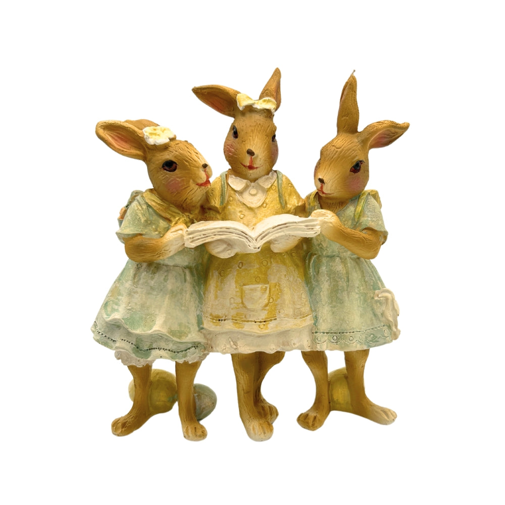 Groupe de trois lapins en résine lisant un livre, robes pastel et détails peints