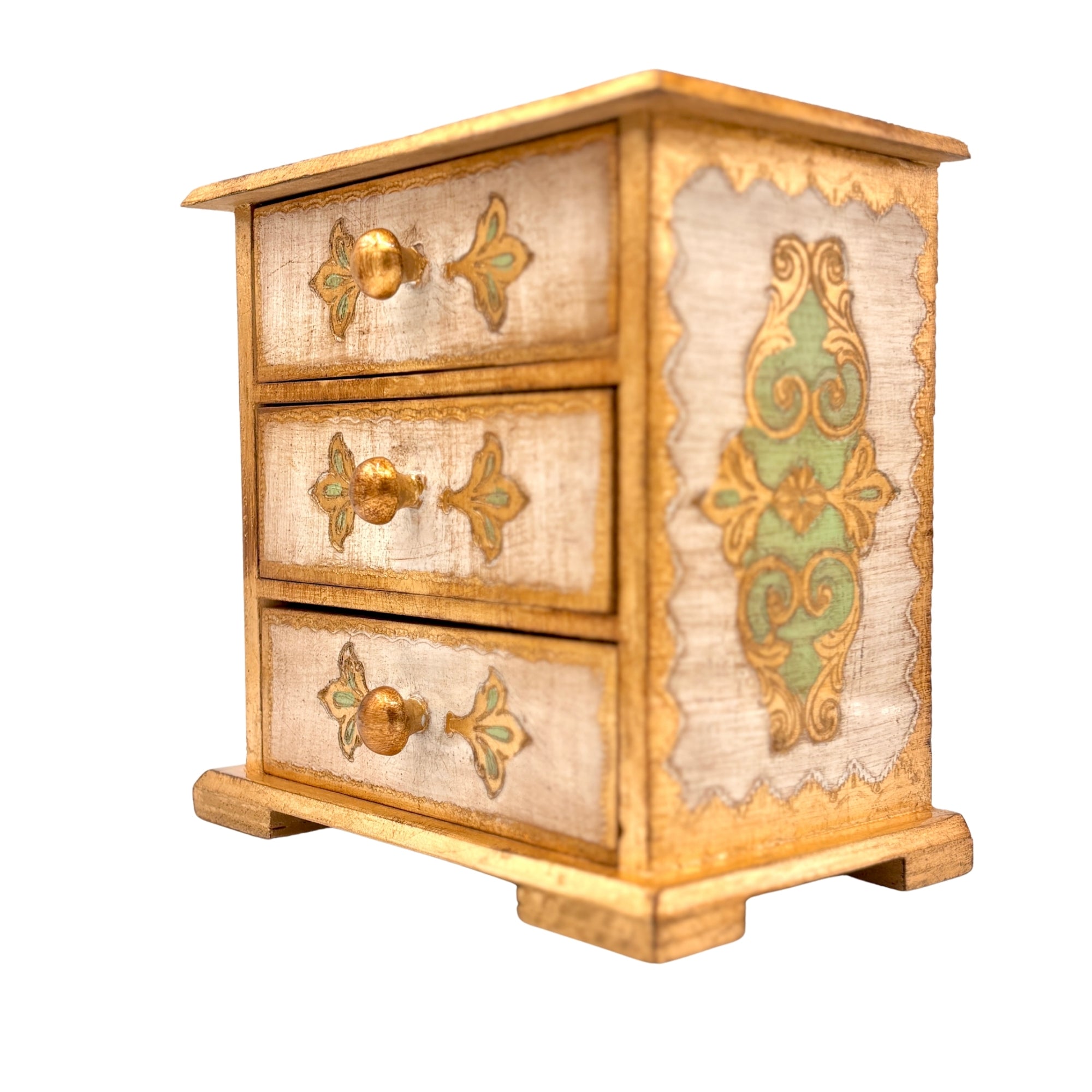Petite commode artisanale à trois tiroirs en bois peint crème et doré, motifs floraux verts et boutons ronds dorés