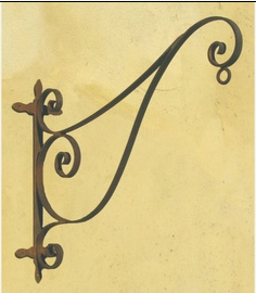 Potence murale en fer forgé noir à volutes, vue de profil sur fond beige