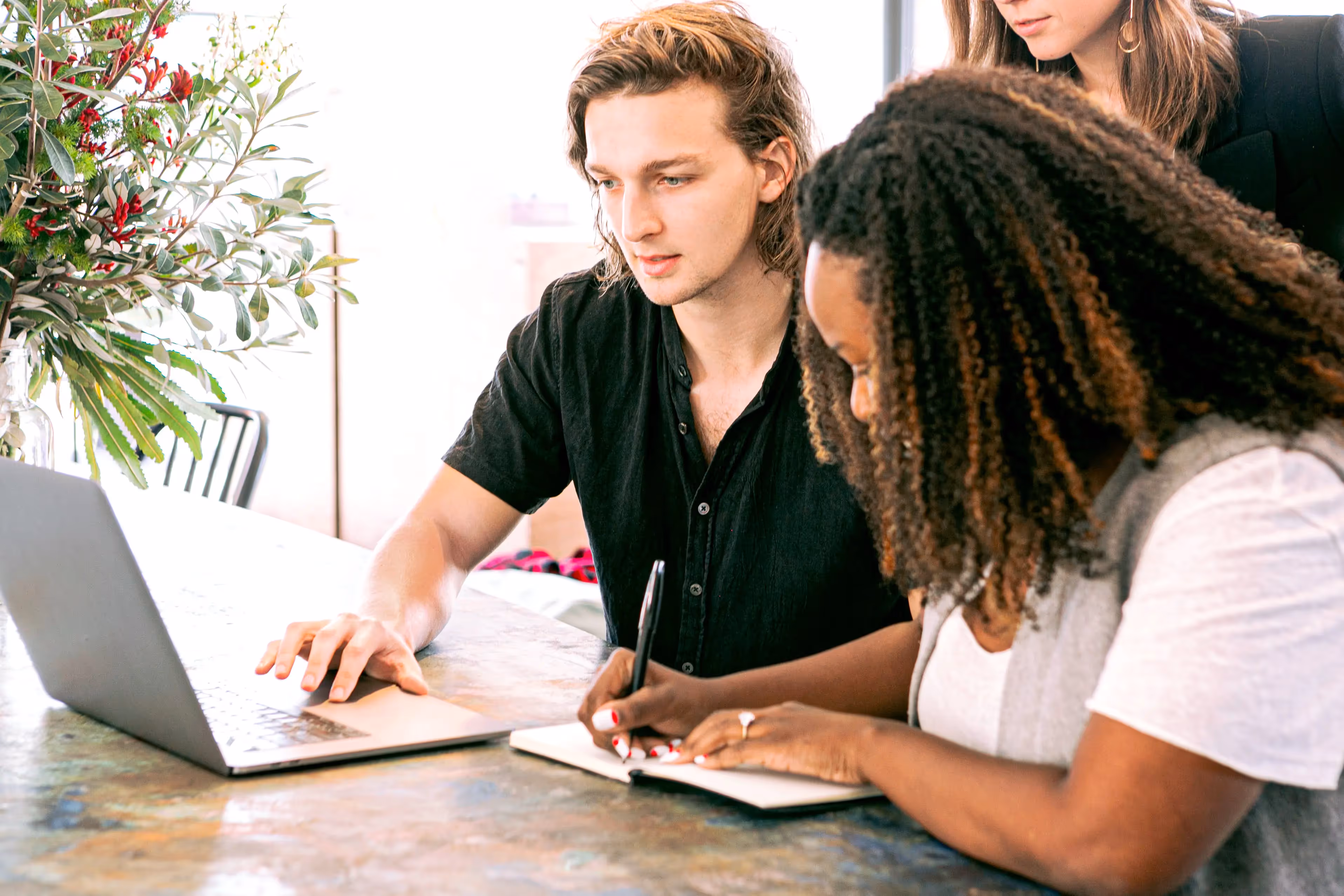 Two people sitting at a table working on a laptop