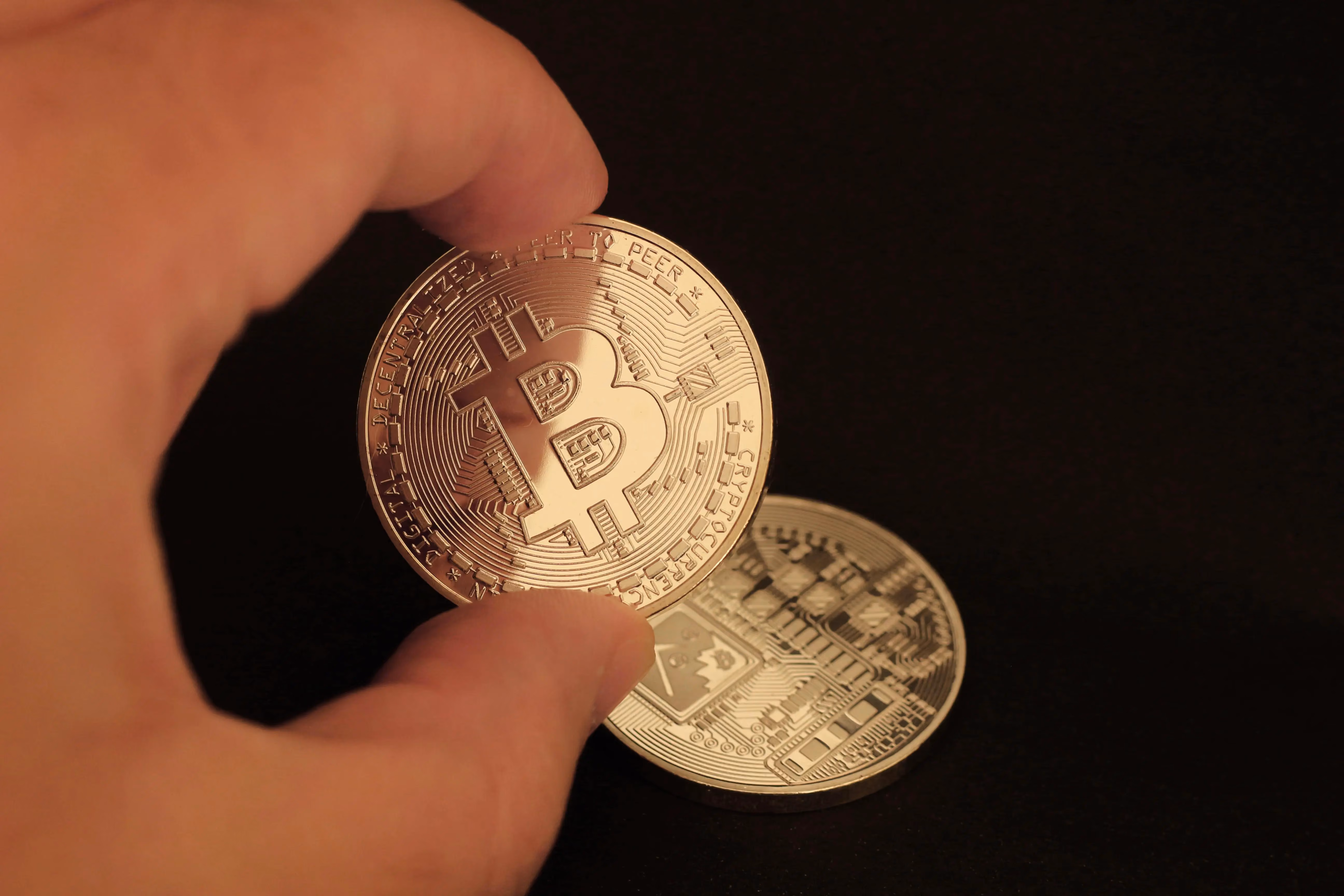 A person holding a bit coin in their hand