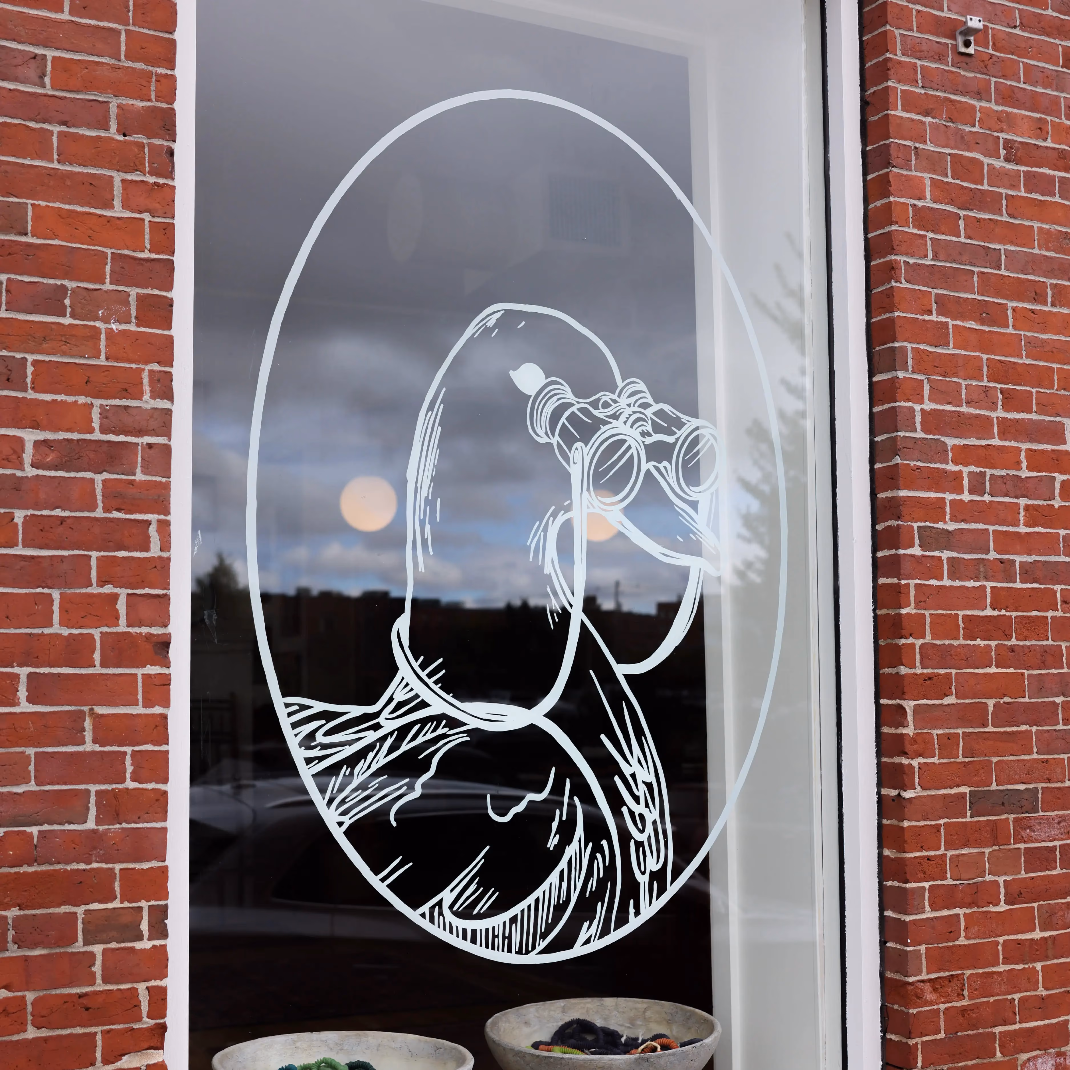Etched glass artwork of person looking through binoculars on window