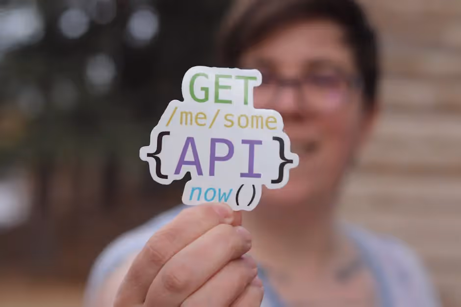 A woman holding up a sticker that says get me some api now