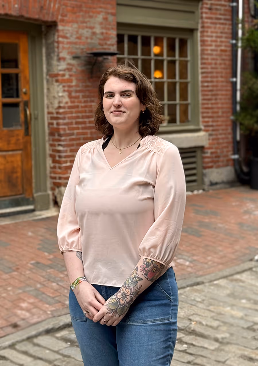 A person standing on a cobblestone street with brick buildings in the background.