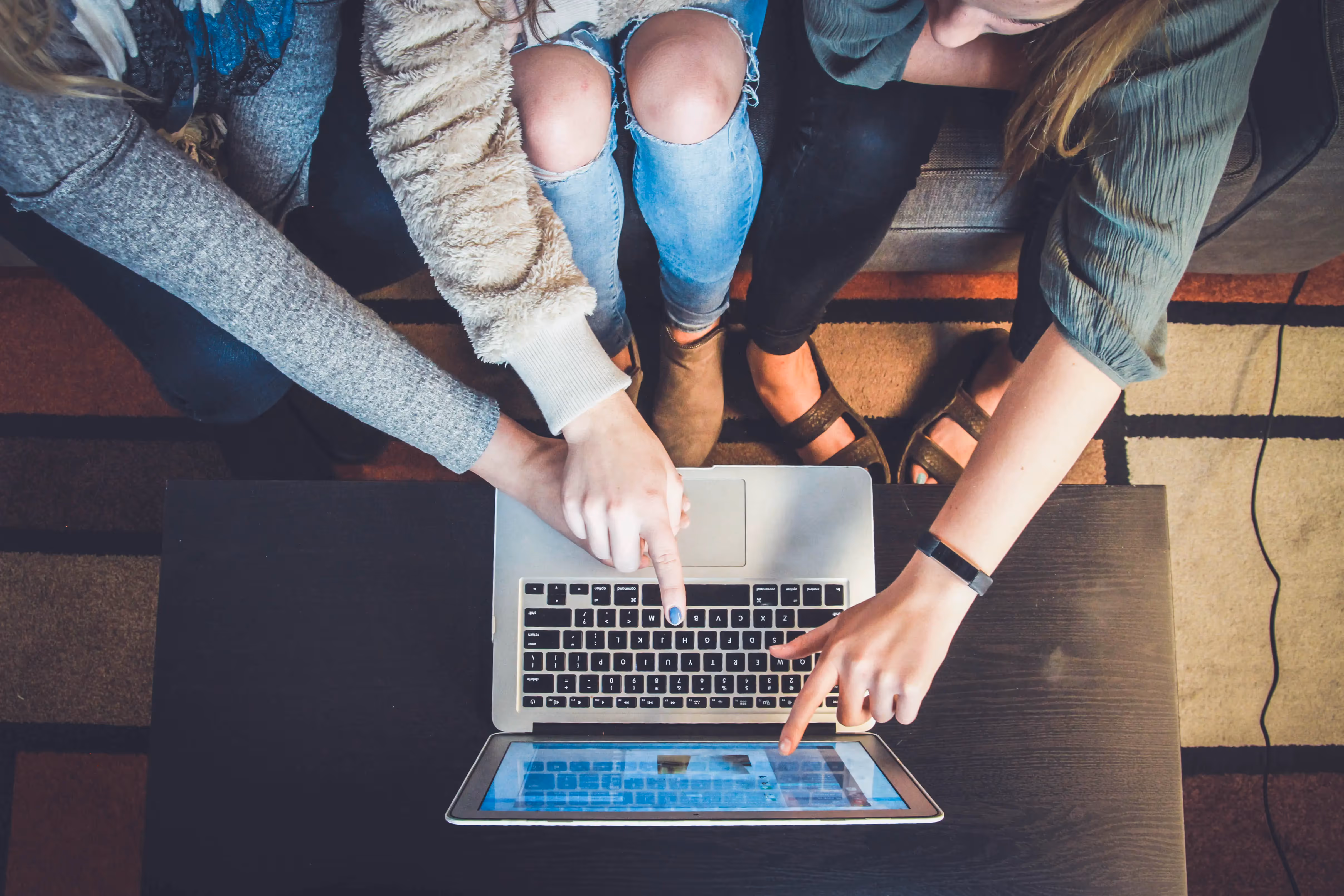 A group of people sitting around a laptop computer