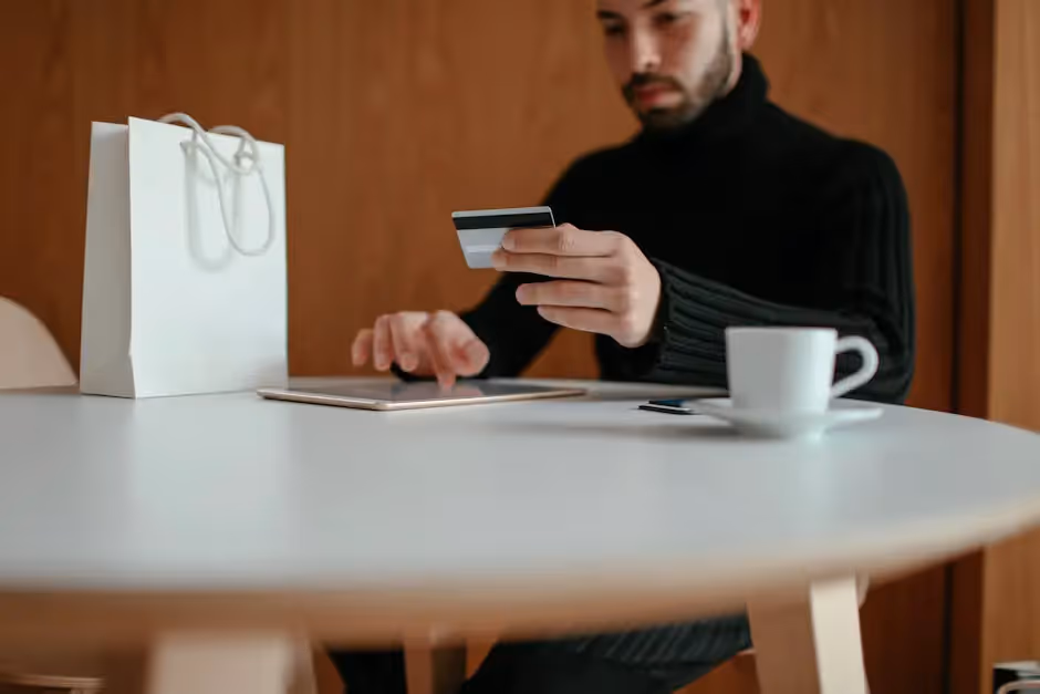 A man sitting at a table holding a credit card