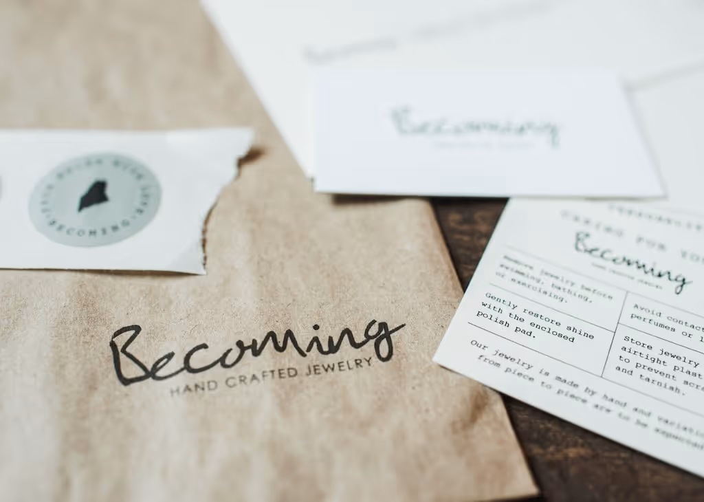 Becoming Jewelry packaging and signage collateral on an ivory cotton-finish background