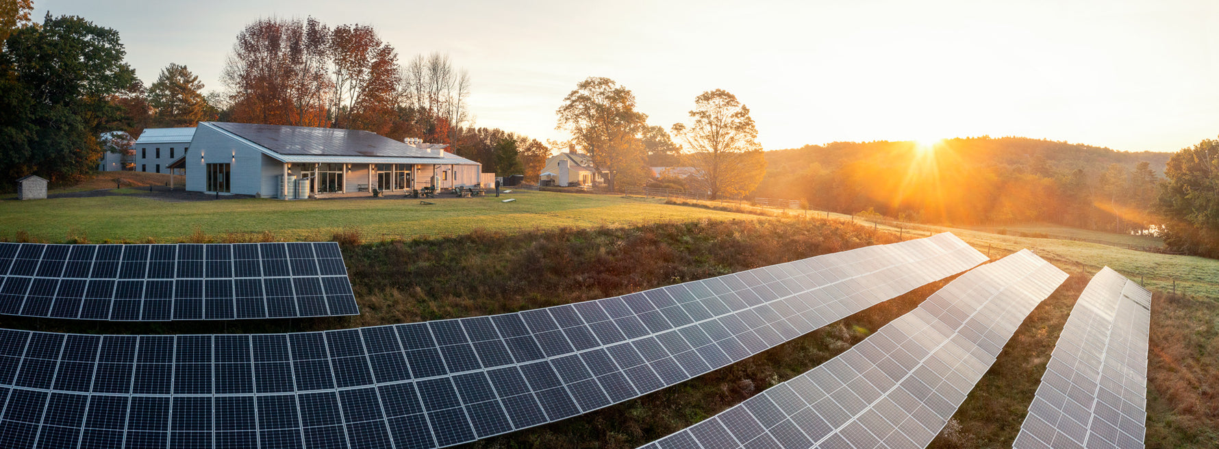 Aerial view of The Ecology School's River Bend Farm campus in Saco, Maine, with its solar array at sunset
