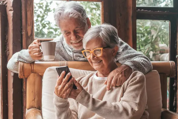 A smiling couple using a tablet outdoors, symbolizing confidence in Home Watch of America's observation and reporting services.