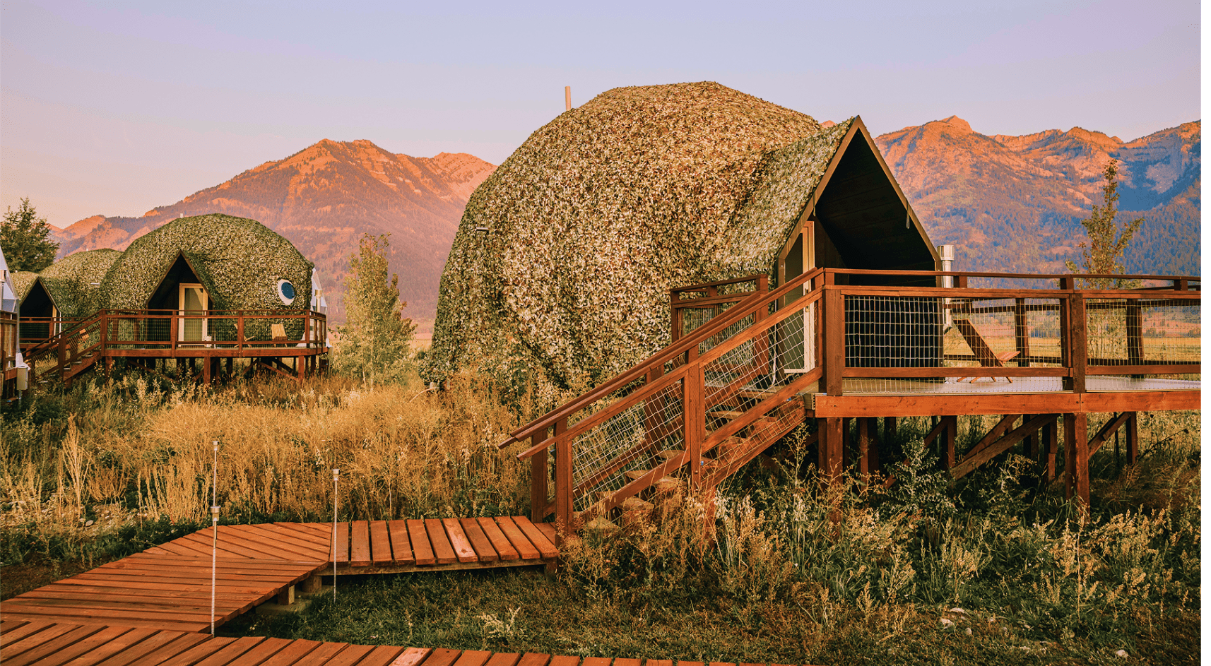 Geodesic dome in front of stream and Teton Mountains.