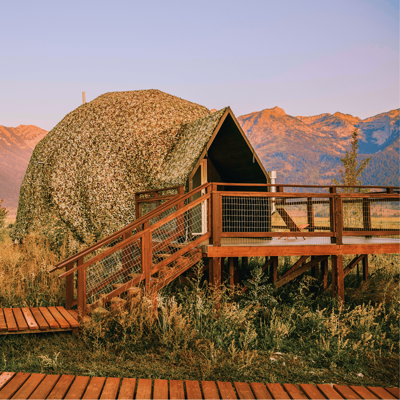Geodesic dome in front of stream and Teton Mountains.