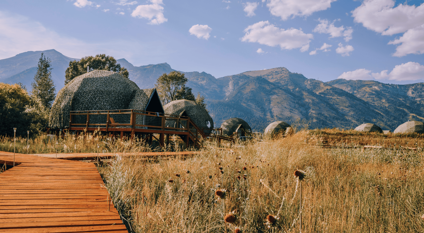 View of geodesic domes and staff building in front of Teton Mountains.