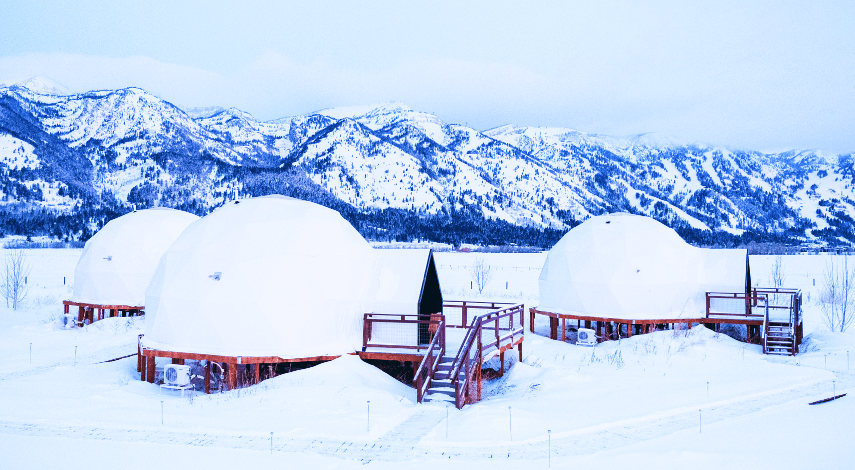 Geodesic dome in front of stream and Teton Mountains.