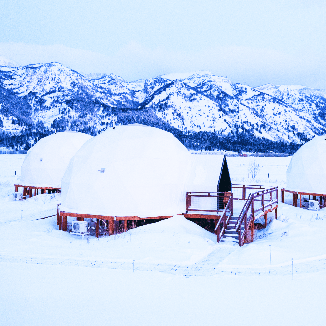 Geodesic dome in front of stream and Teton Mountains.