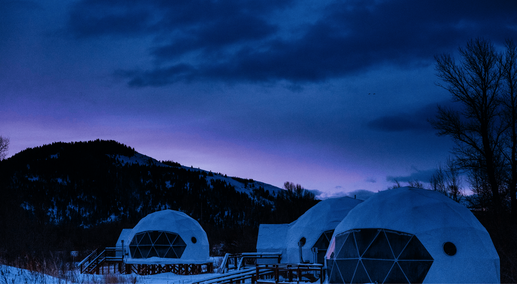 View of geodesic domes and staff building in front of Teton Mountains.