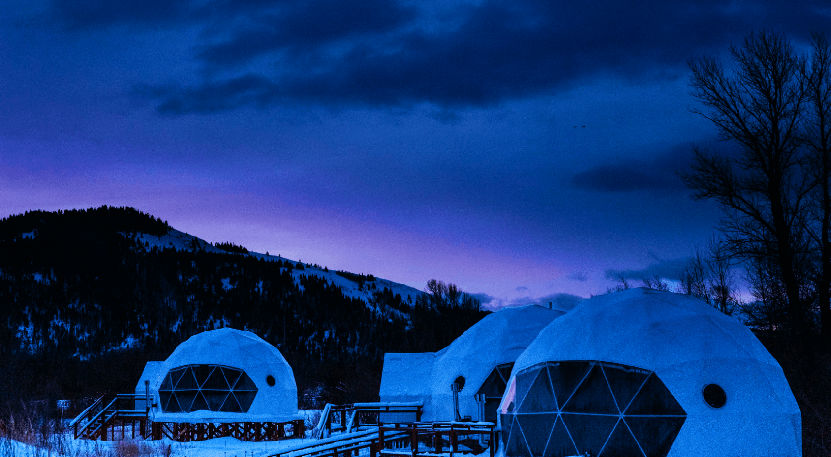 View of geodesic domes and staff building in front of Teton Mountains.