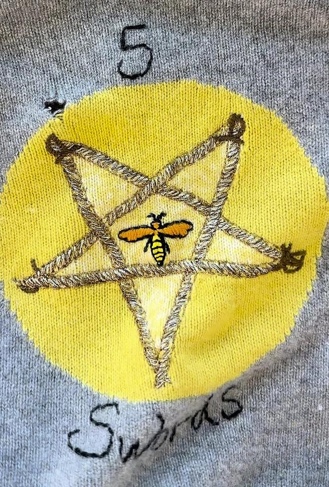 A moth hole beside the embroidered star on a grey cashmere sweater
