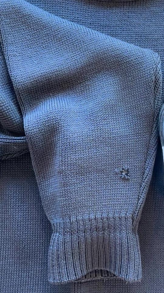 A hole in the sleeve of a navy cotton sweater