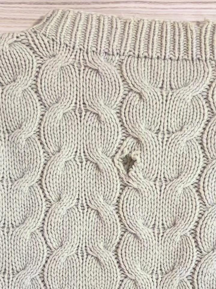 A hole in the cable front of a cream sweater