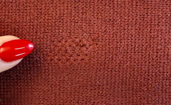 FXRY's machine darn sample on a rust-colored knit