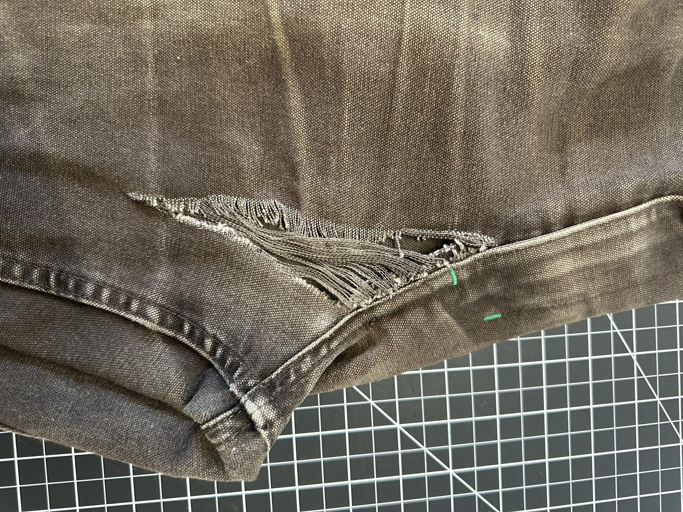 Dark work pants ripped open along the inner thigh