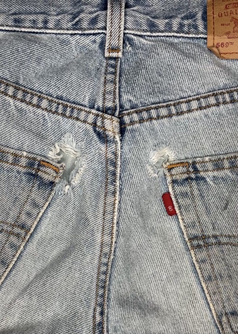 Jeans with both back pocket corners torn through