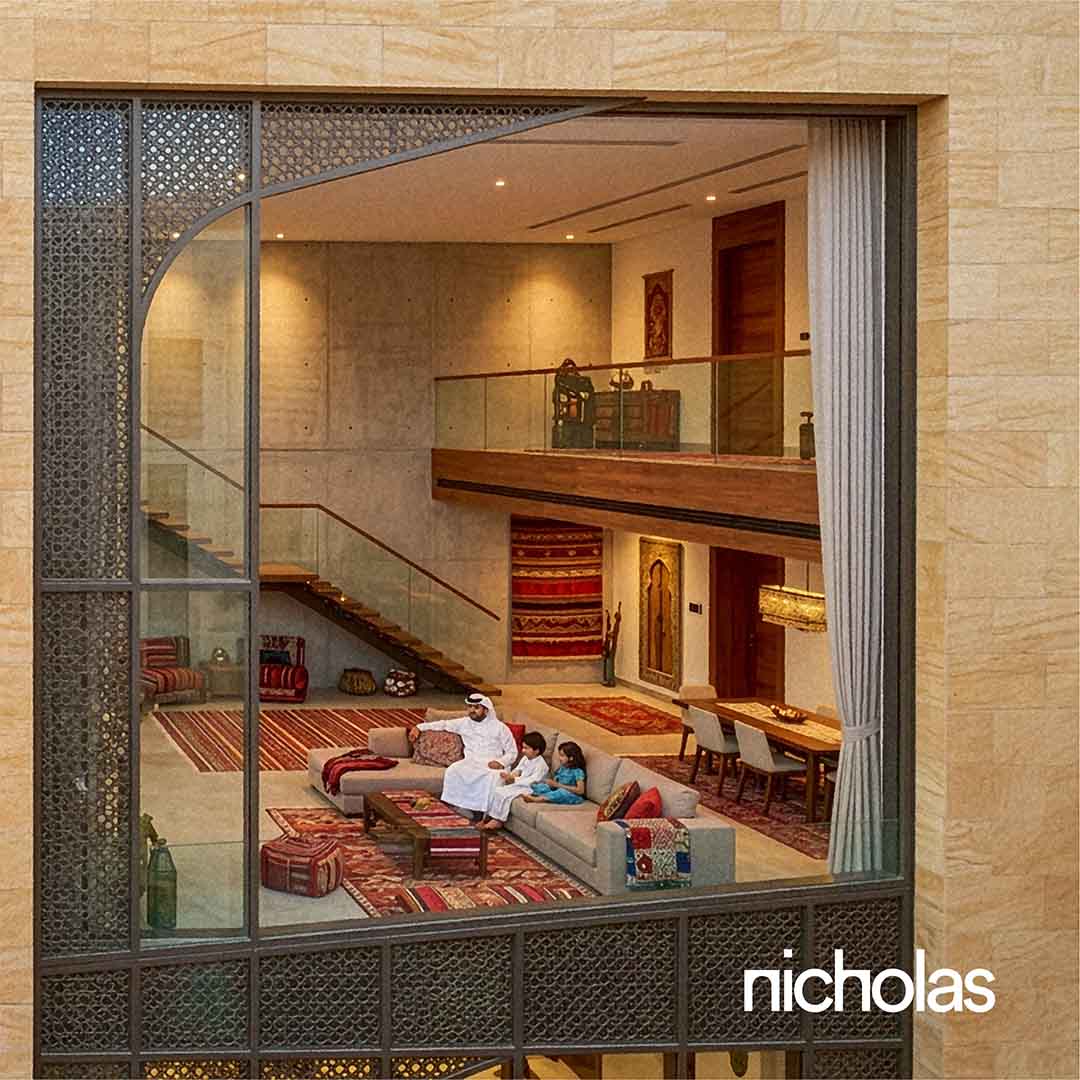 A view of a residential building facade opening into a living room where a father and two children sit together on a sofa, suggesting everyday domestic life within a contemporary, community-oriented urban environment