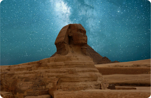 The Great Sphinx of Giza stands majestically under a clear, starry night sky. The ancient limestone statue, with its lion's body and human head, is illuminated by the soft light, highlighting its weathered but awe-inspiring features. The Milky Way galaxy is visible in the background, adding a mystical and timeless quality to the scene.