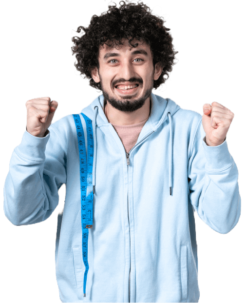 A joyful man with curly hair, wearing a light blue hoodie, stands with his fists raised in triumph. He has a bright smile on his face, and a blue measuring tape is draped around his neck, symbolizing weight loss success. The background is plain white, emphasizing his expression and gesture of victory.