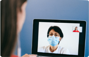 a lady looking at a laptop screen that showing a video call with a doctor
