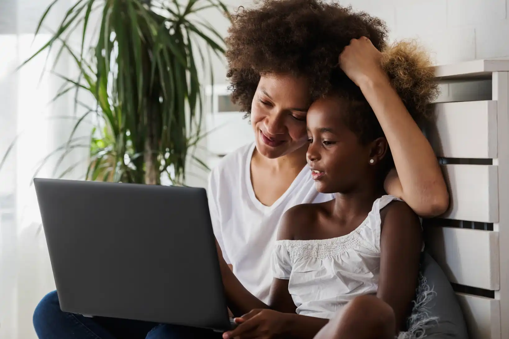 Female non traditional student completing online courses with daughter alongside