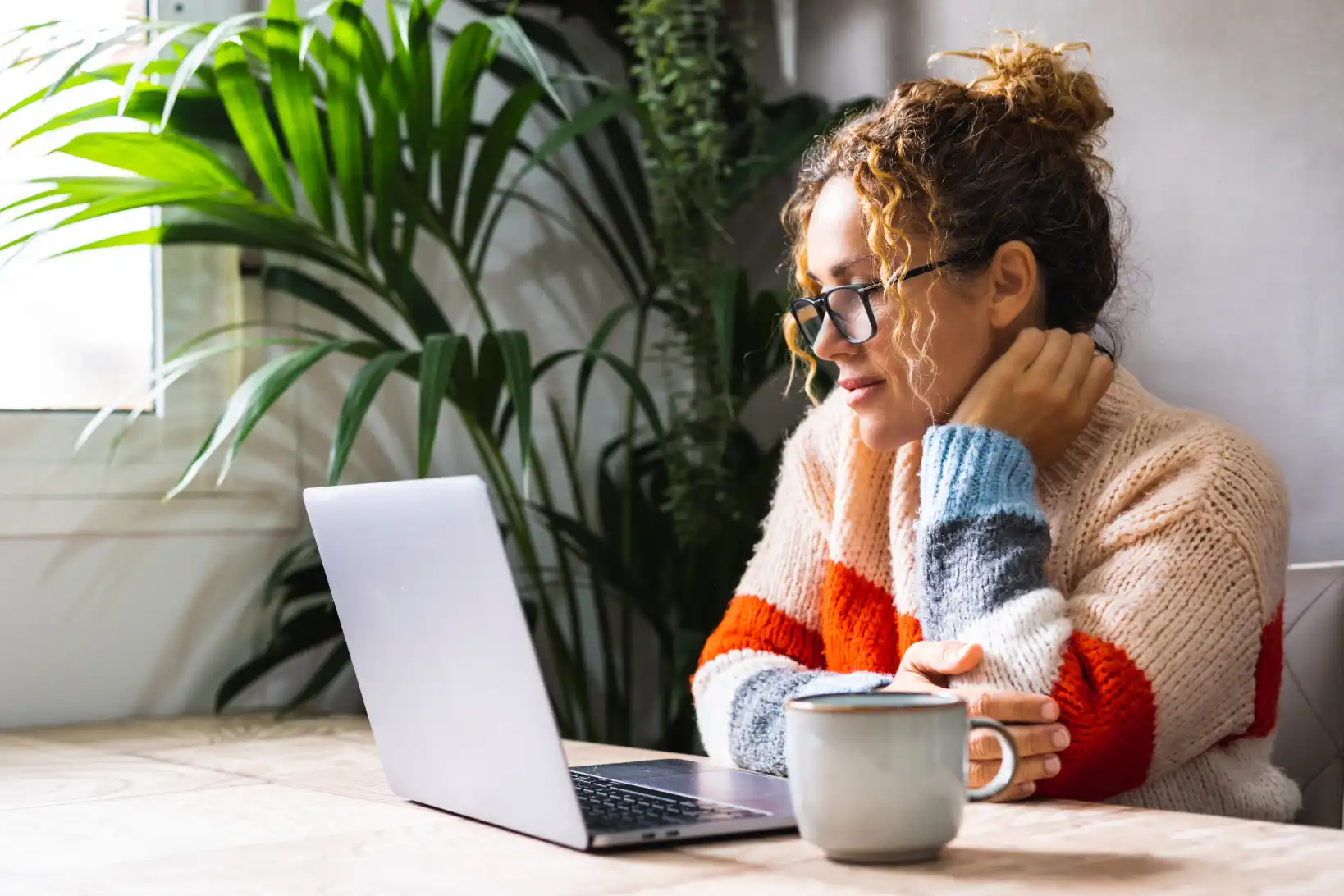 Curly-haired woman in orange sweater studying online as a non traditional student