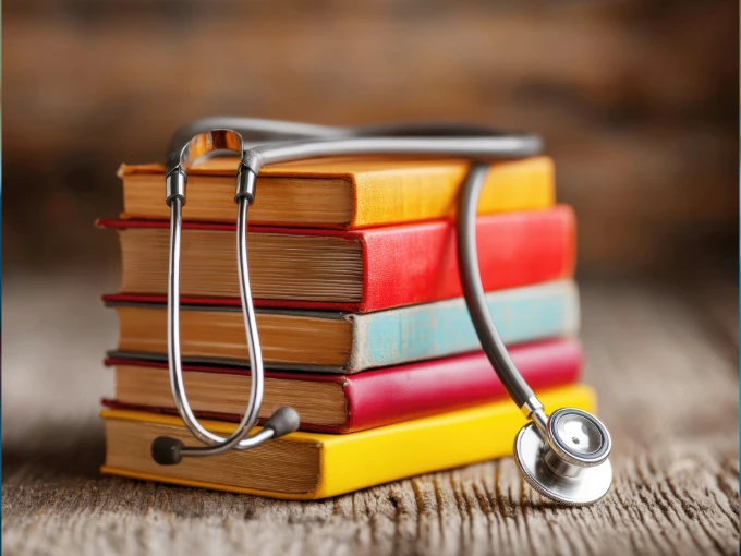 A pile of books for nurses with a stethoscope on top.