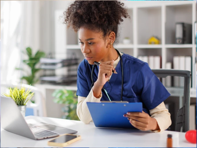 LPN studying online RN nursing program on laptop while reviewing clinical notes for LPN to RN bridge program 2026