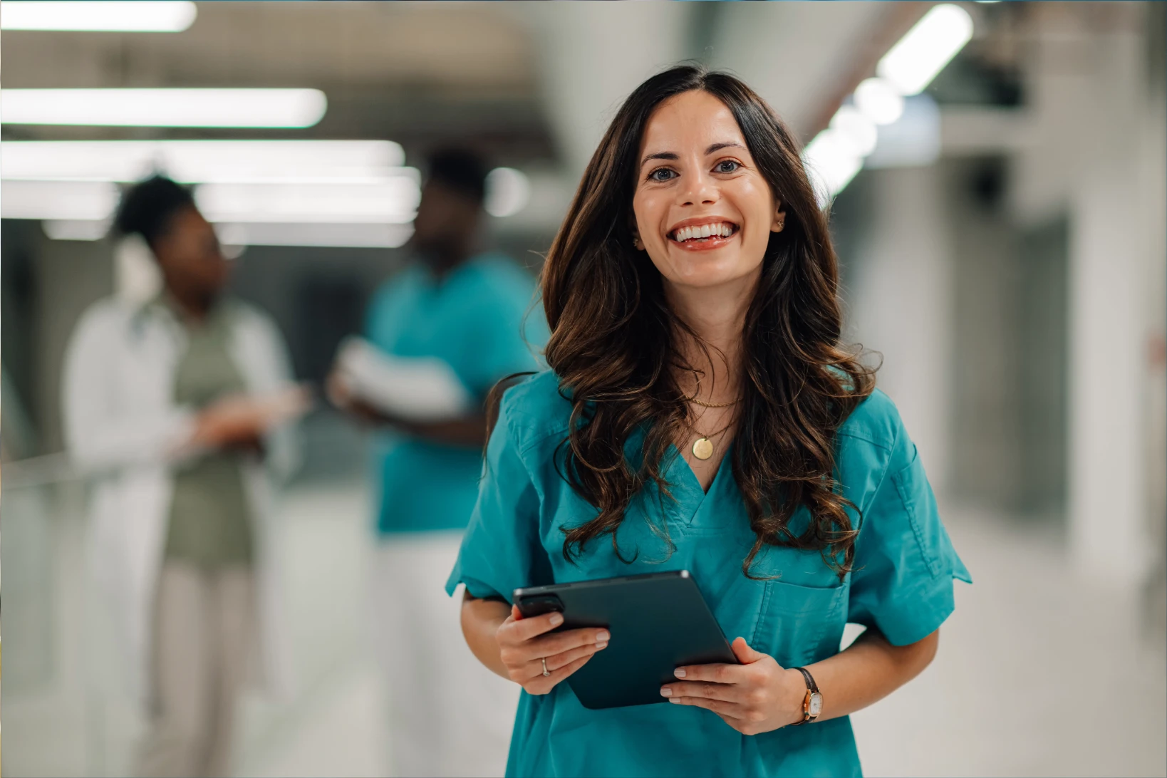 Registered nurse in scrubs holding a tablet in a hospital hallway, representing RN license transfer and nursing career mobility