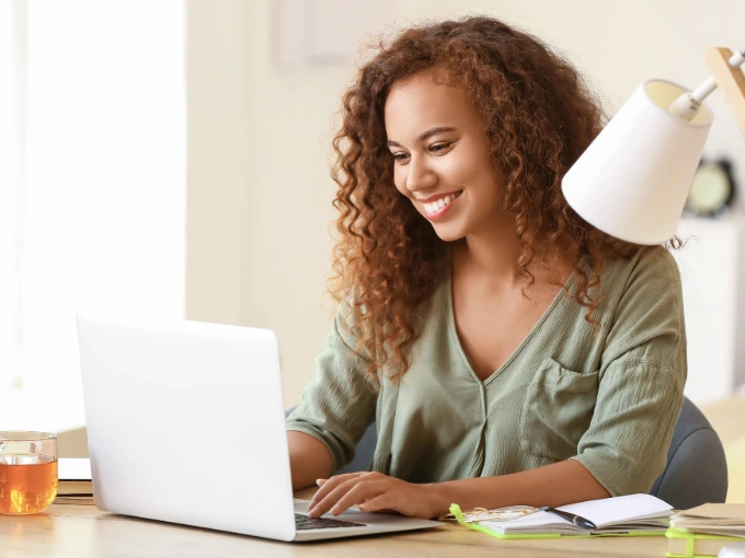 Adult female in casual clothes looking at college credit by exam options on laptop
