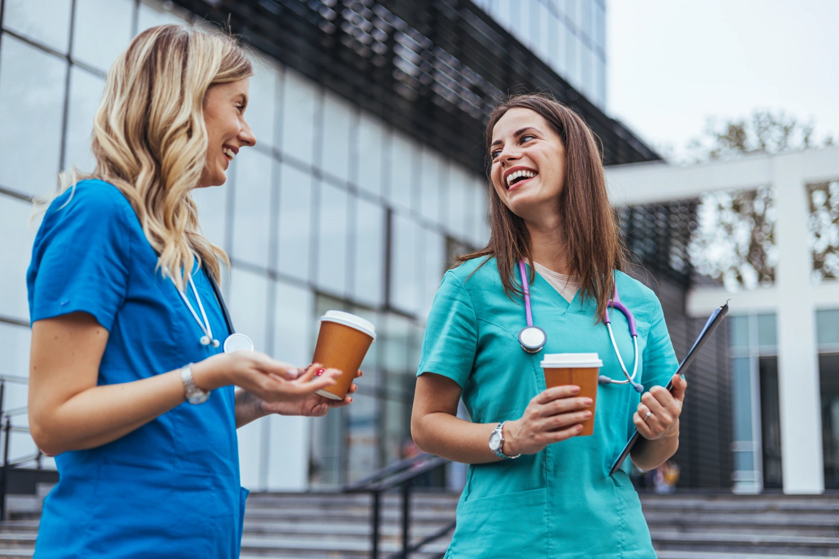 Two nurses chatting about online nursing school options outside of their hospital