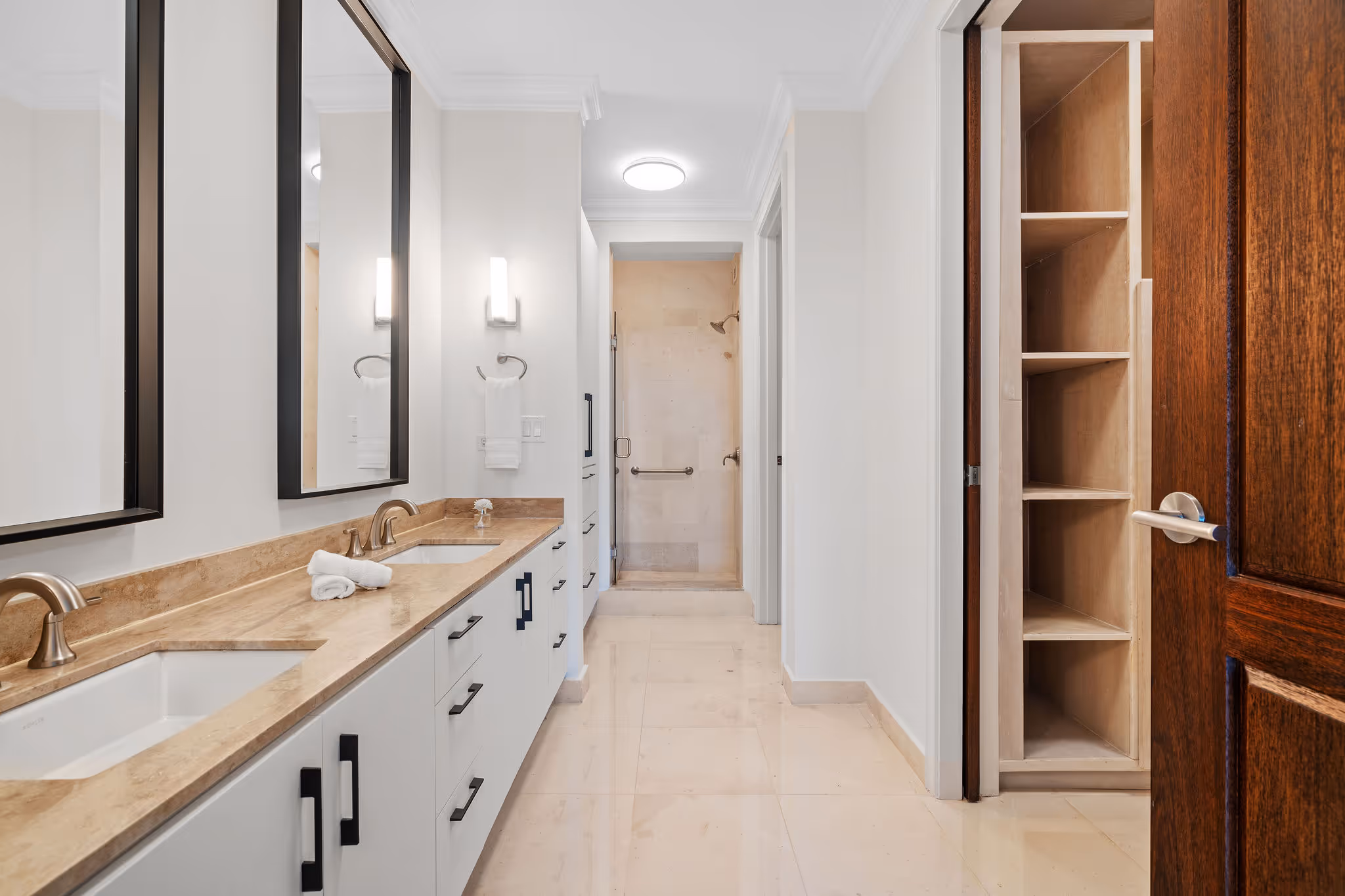 19. Country Club Villas F302 Image 12: Luxurious en-suite bathroom featuring a double vanity with marble countertops, sleek black-framed mirrors, and a spacious walk-in shower.
