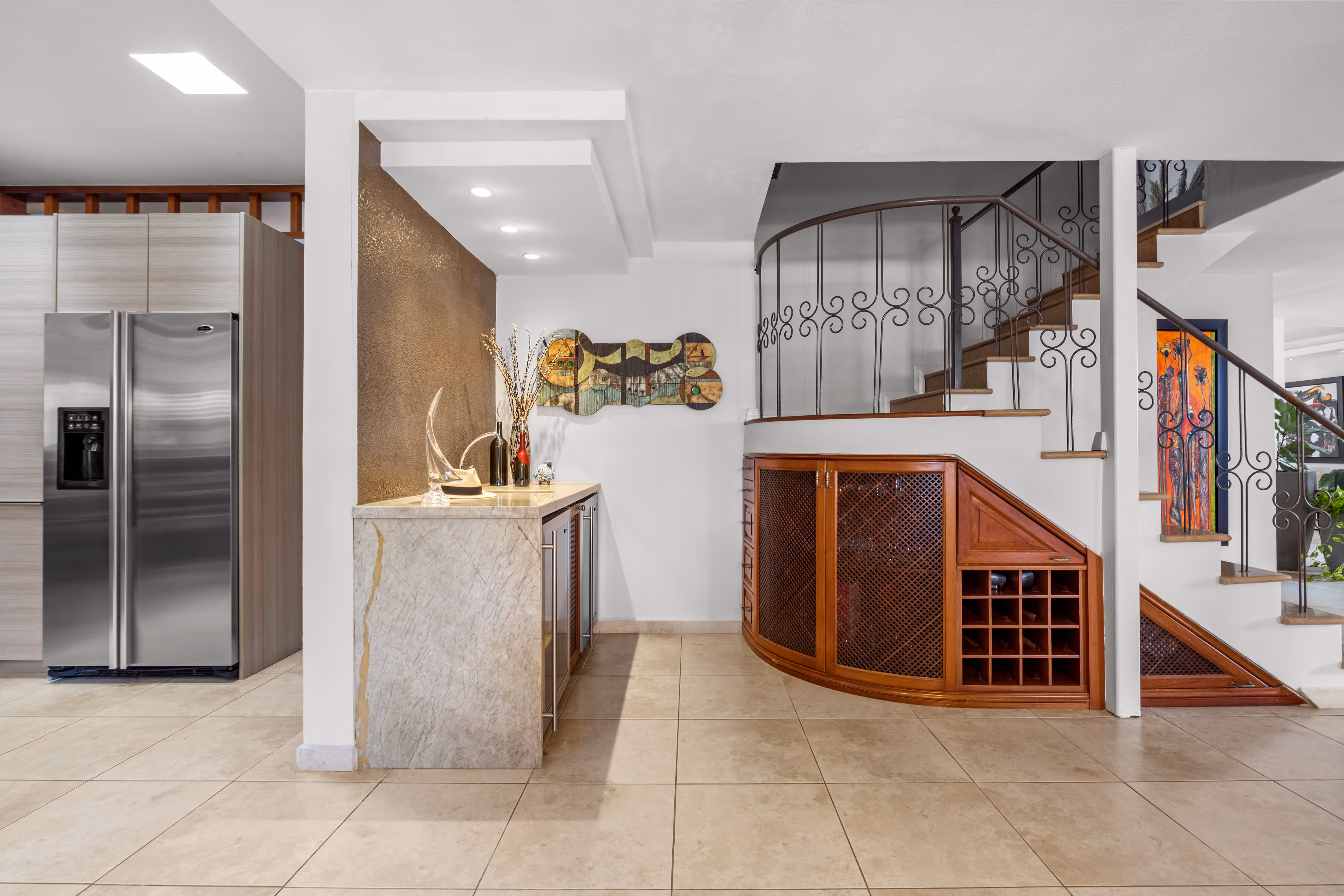Elegant staircase and built-in wine storage in a custom-designed home in Villas Reales, Guaynabo, with a stylish kitchen in the background.