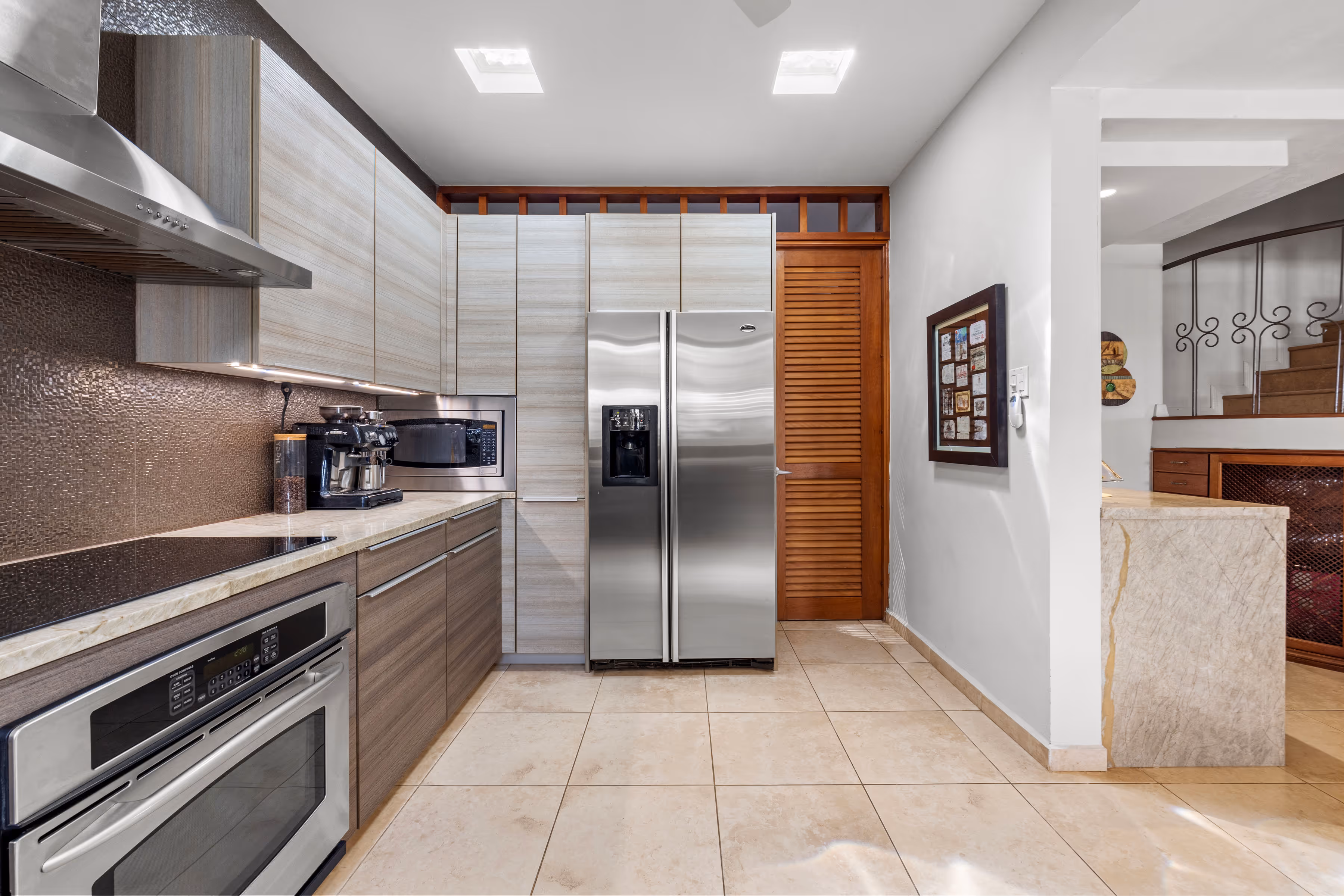 Contemporary kitchen with sleek wood cabinetry, stainless steel appliances, and a spacious layout in a Villas Reales luxury home.