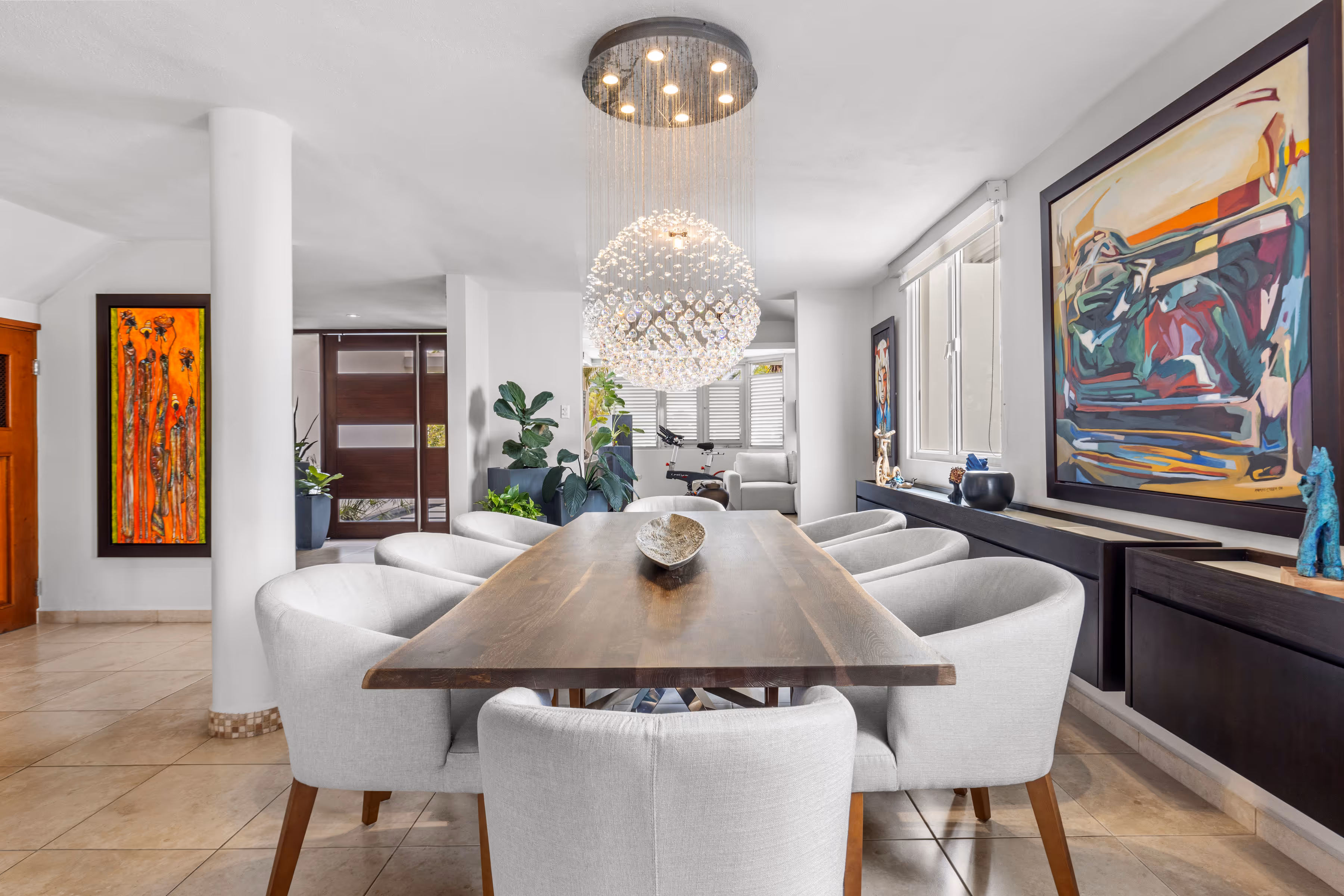 Stylish dining area with a statement chandelier, wooden table, and contemporary decor in a modern Villas Reales home.