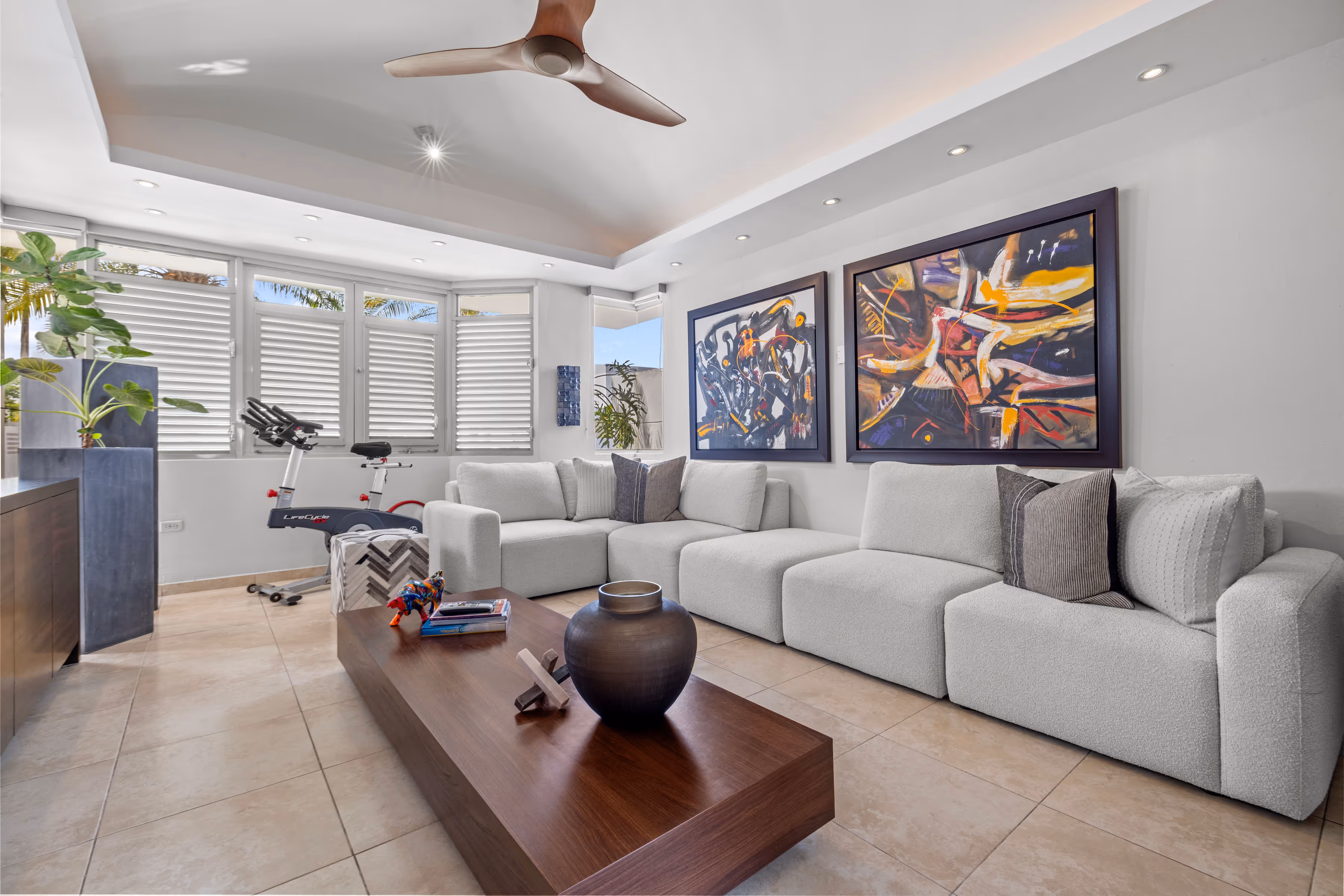 Cozy entertainment room with plush seating, artistic wall decor, and large windows providing natural light in a Villas Reales residence.