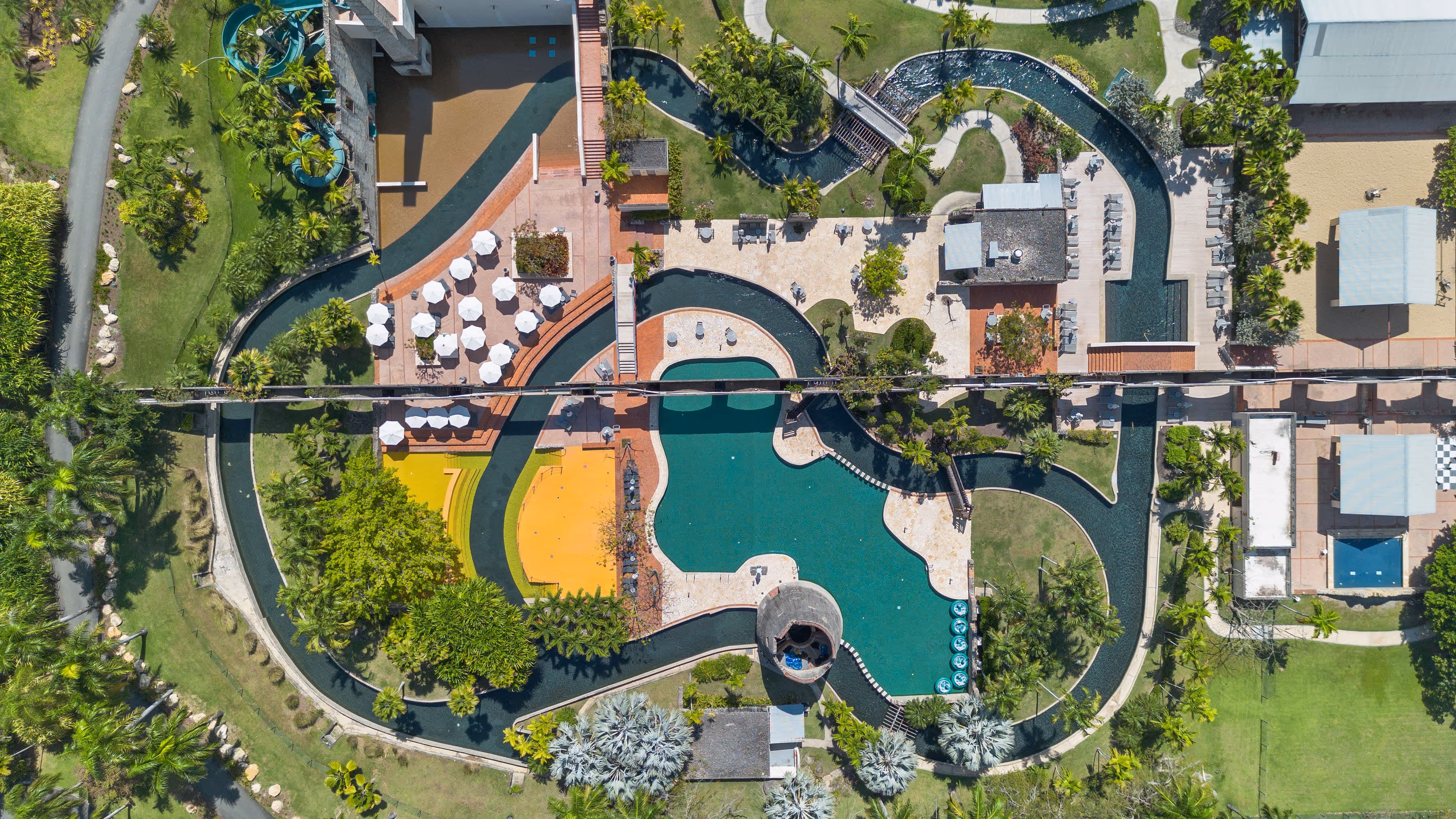Aerial view of The Watermill water park with winding pools, lazy river, and vibrant landscaping at Dorado Beach Resort
