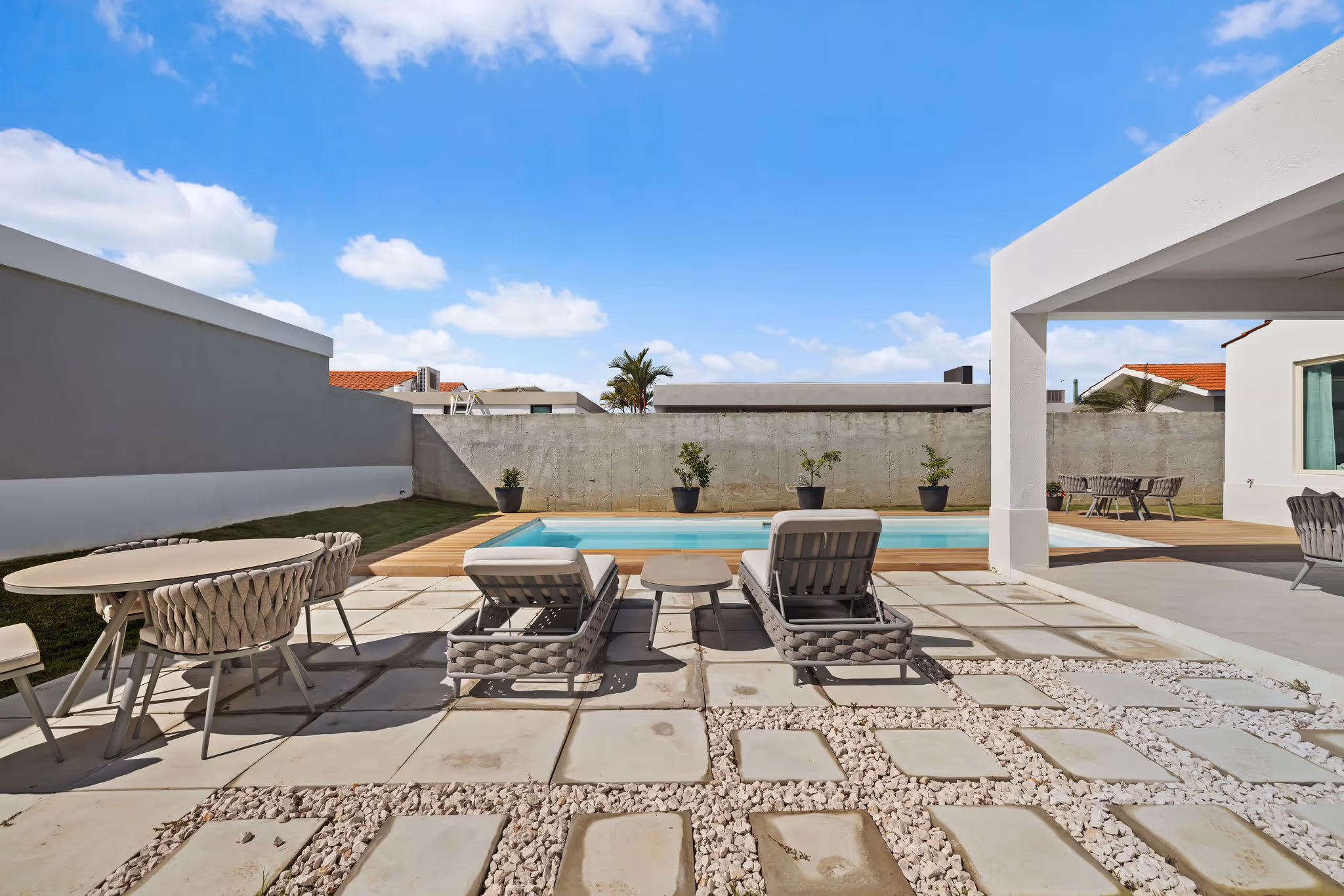 Poolside patio with sun loungers and dining area in private backyard of Isla de las Flores luxury home