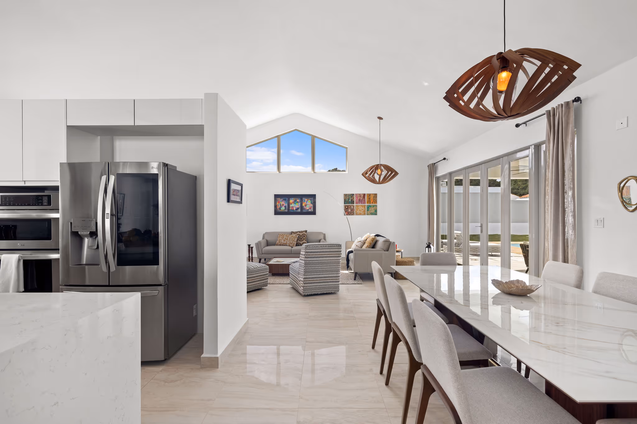 Dining and living space with glass sliding doors and stylish lighting in solar-powered Sabanera Dorado home