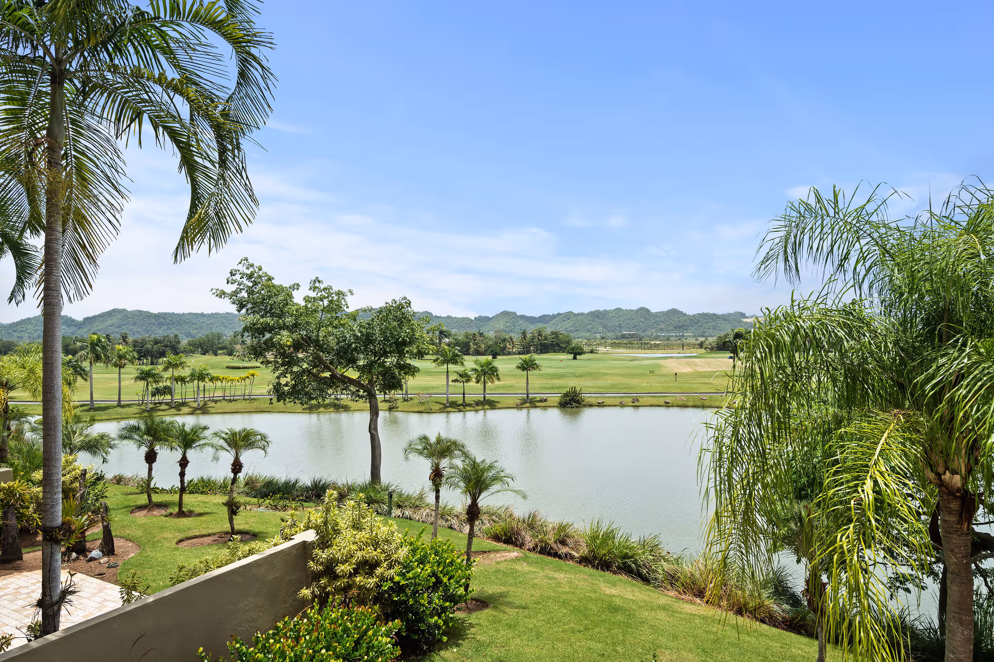 Lush tropical landscaping and golf course views with serene pond from second-floor residence in Plantation Village