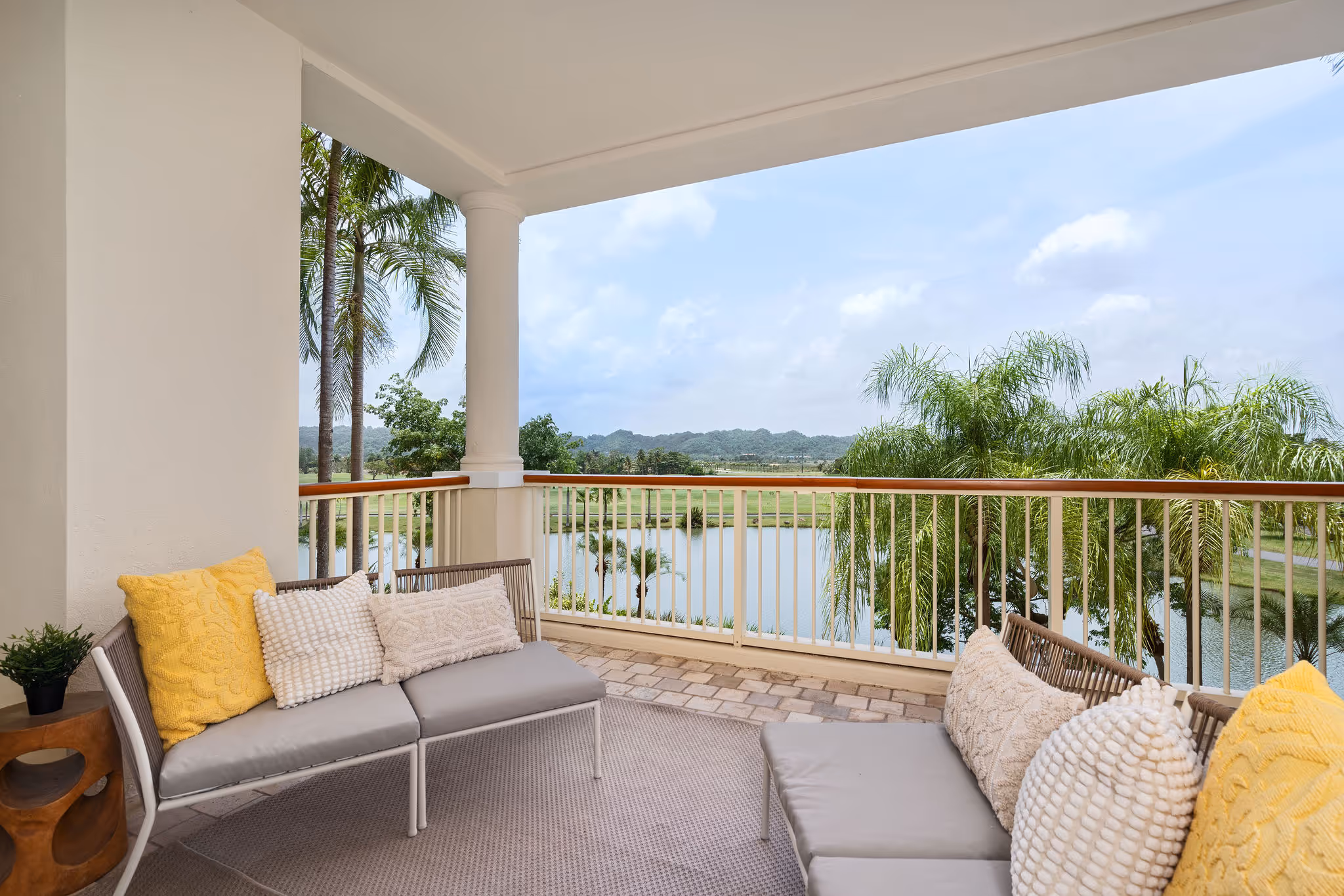 Covered balcony with outdoor seating and serene water and mountain views at Plantation Village, Dorado Beach Resort