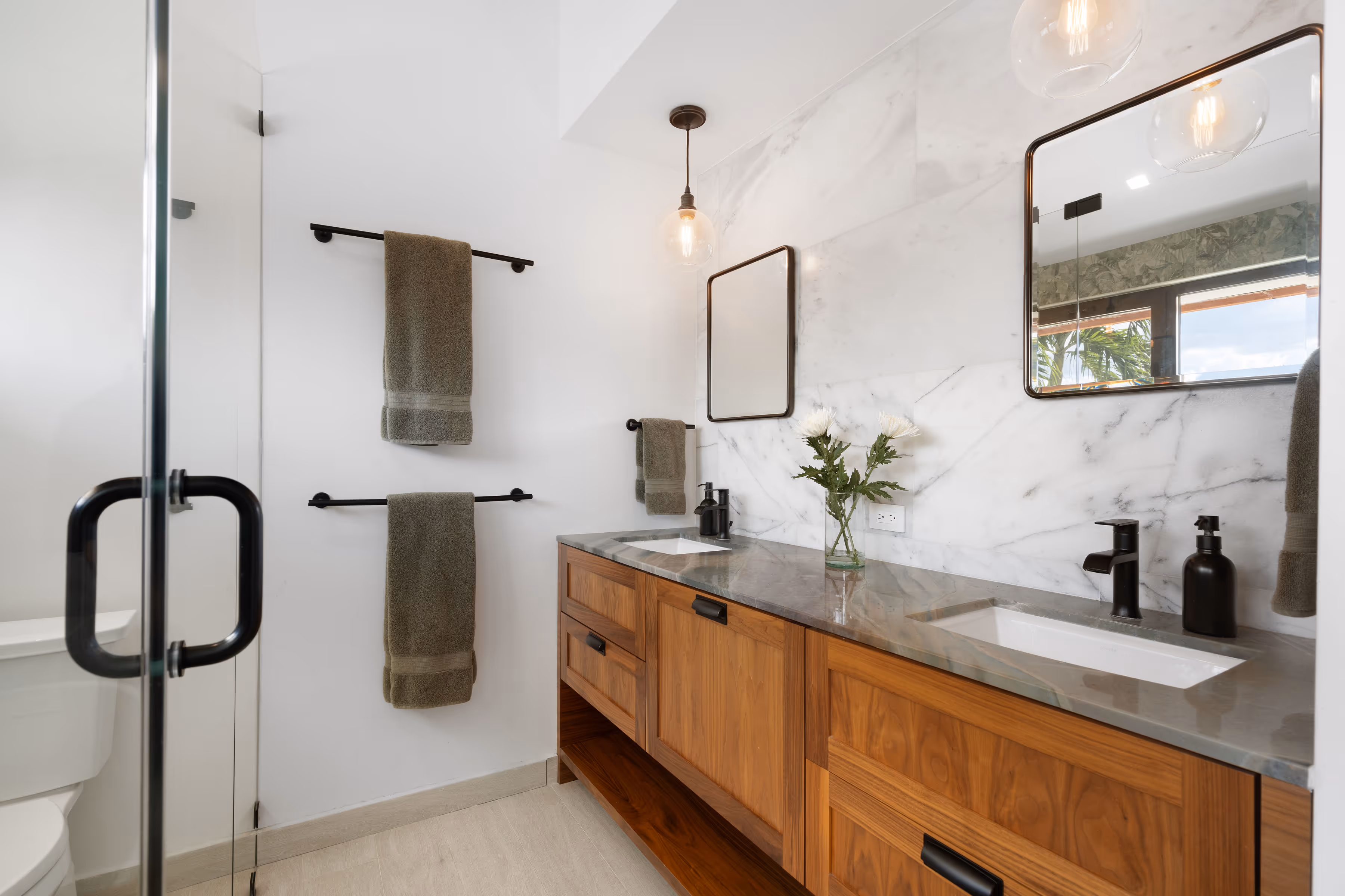 Dual vanity bathroom with glass-enclosed shower and modern fixtures